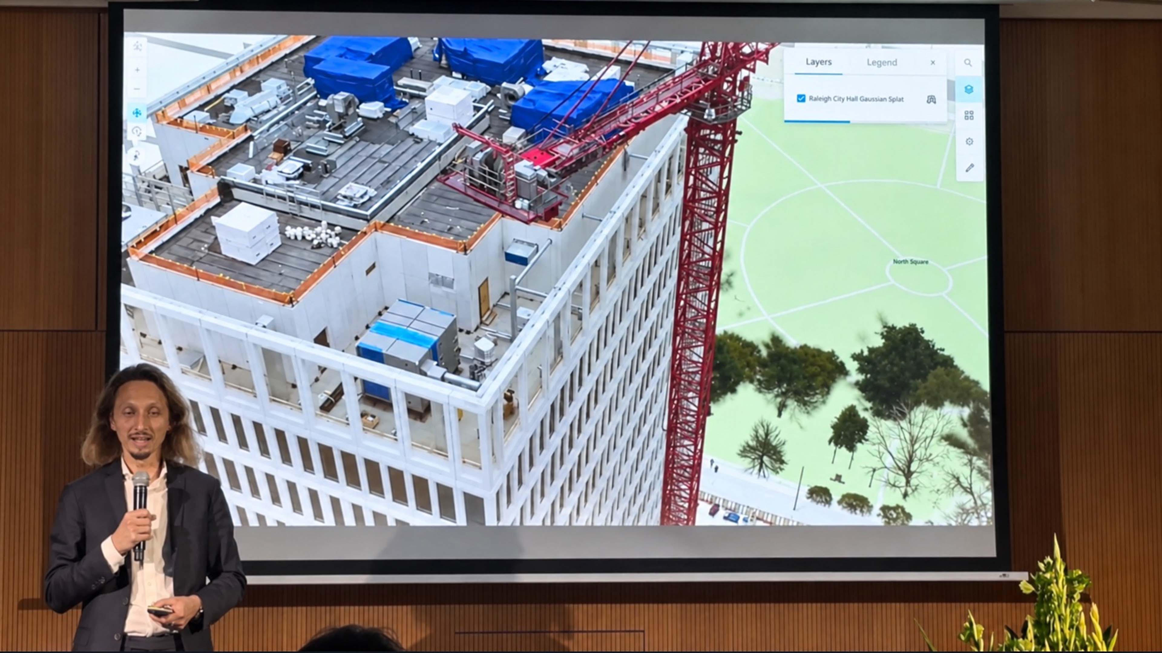 Bühnenfoto von Konrad Wenzel bei seinem Vortrag auf der INTERGEO 2026 in München, im Hintergrund eine Großprojektion mit einem 3D-Kartenausschnitt der Niederlande